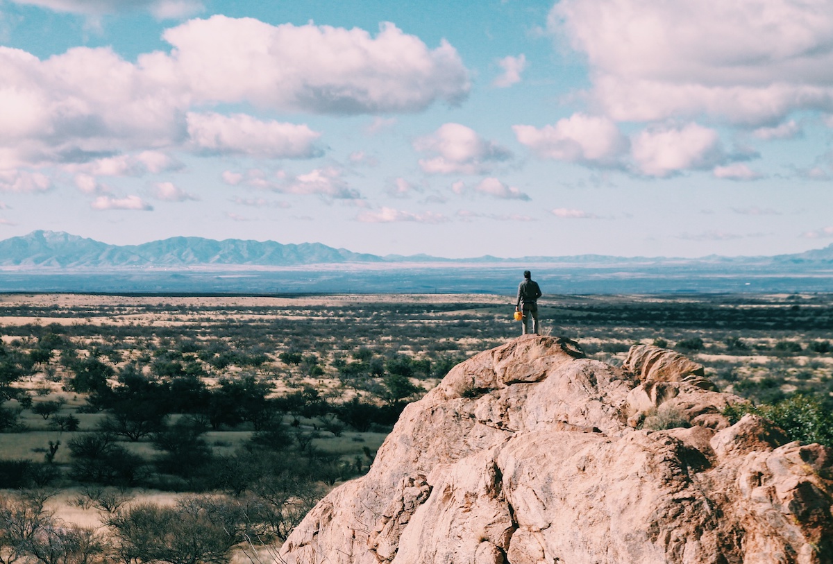 NOLS student stands on rocky outcrop at Cochise Stronghold and looks out at desert landscape