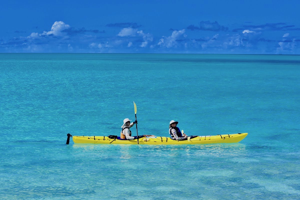 NOLS participants paddle a yellow double kayak in turquoise water in Baja