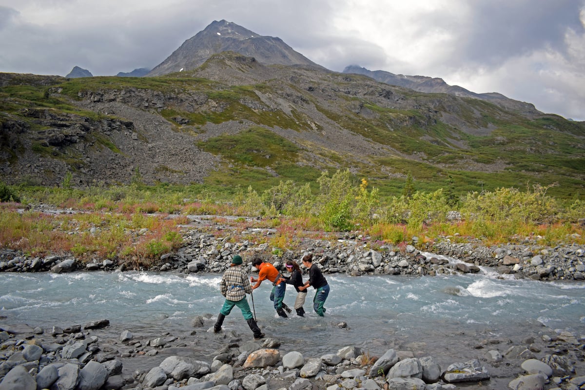 our NOLS students cross a river in Alaska's mountains