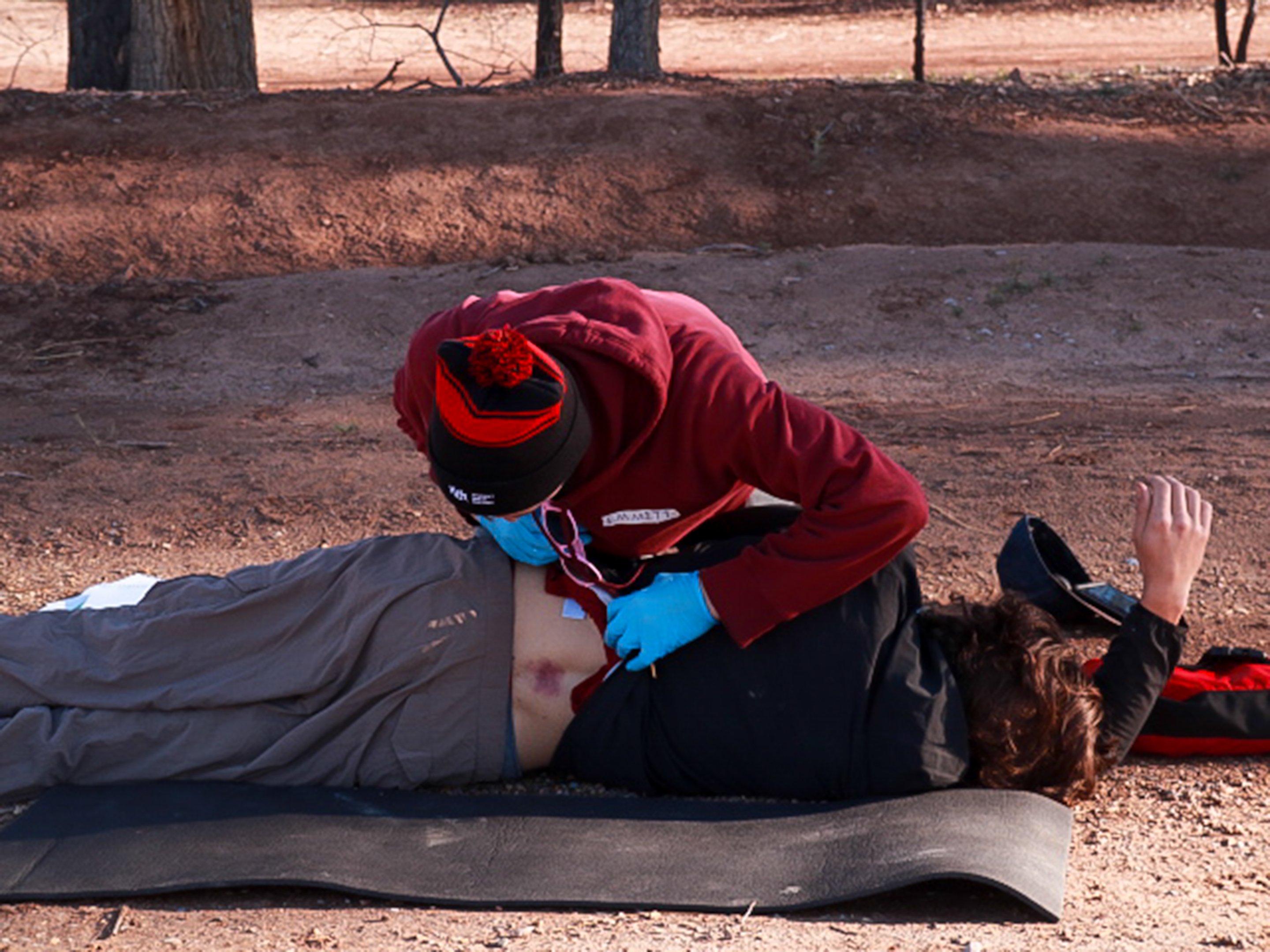 A rescuer log rolls a patient to check his bruised spine.