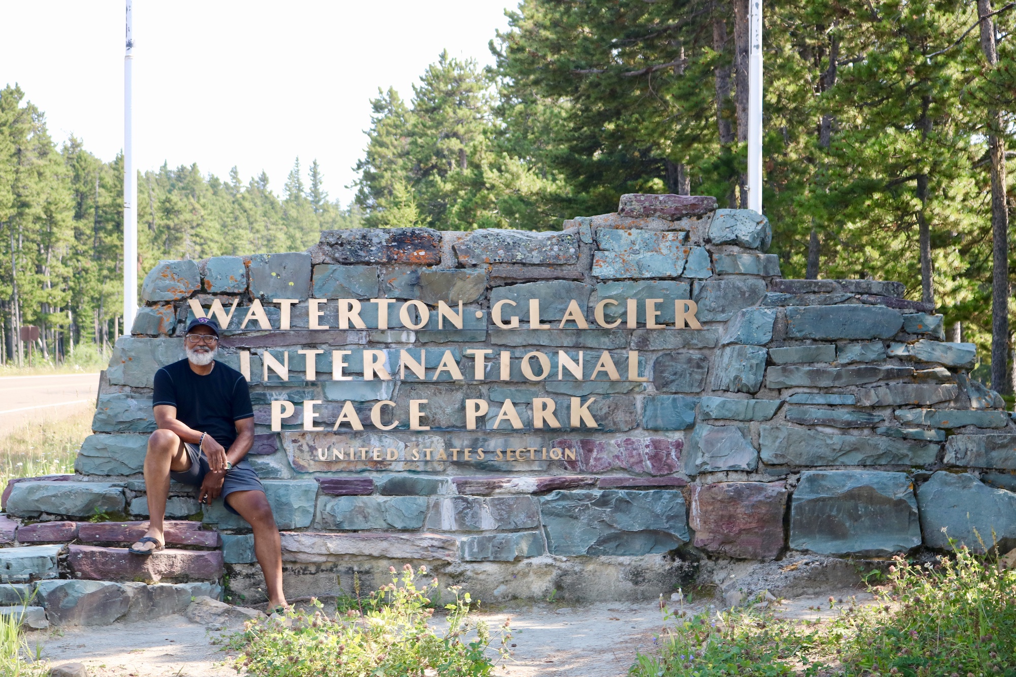 Carter McBride at the entrance sign to Waterton Glacier International Peace Park