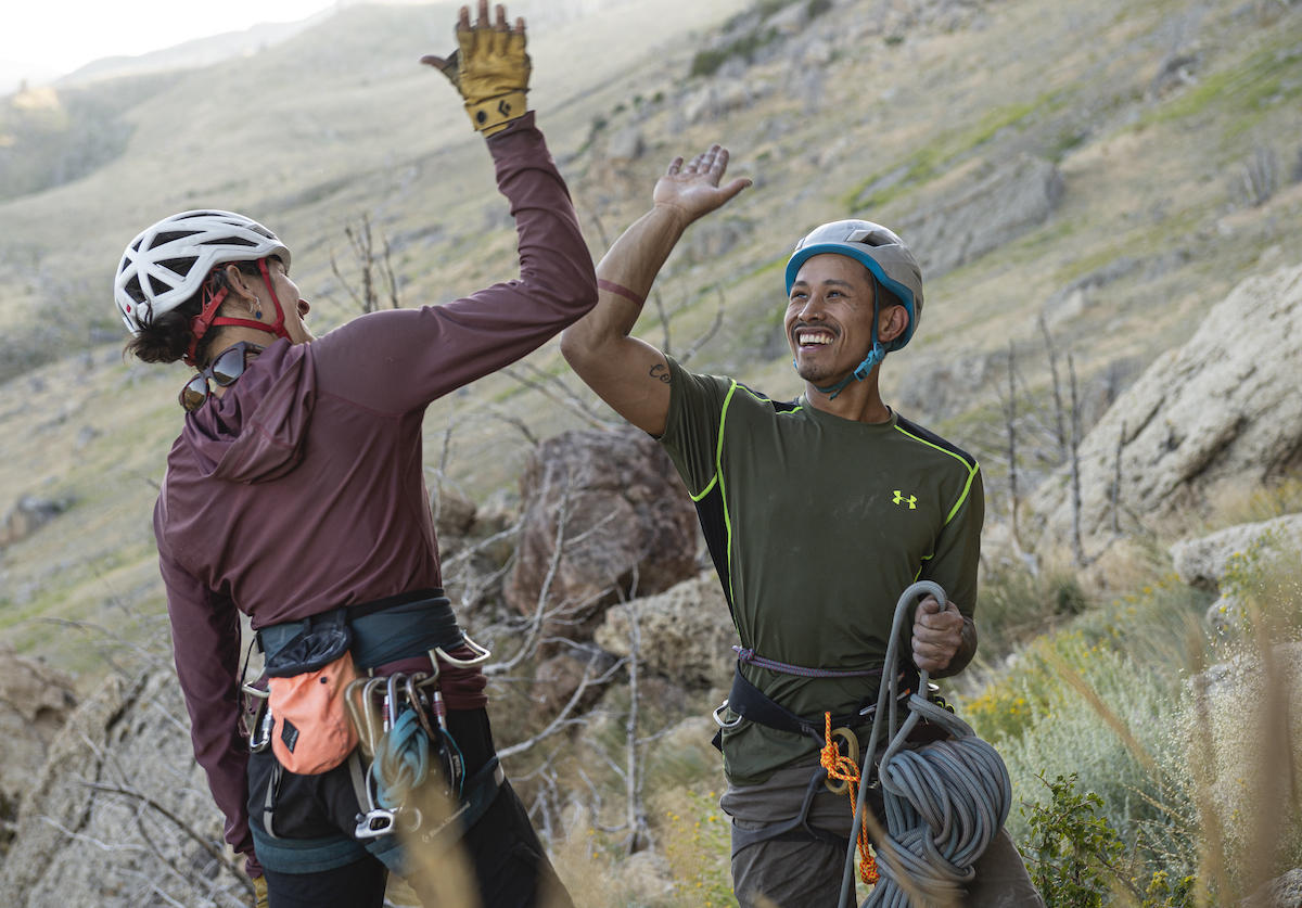 two smiling rock climbers high five