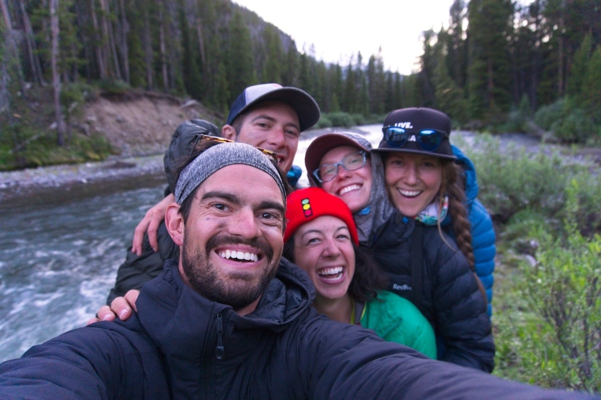 selfie photo of five smiling students on a cloudy day with a river in the background