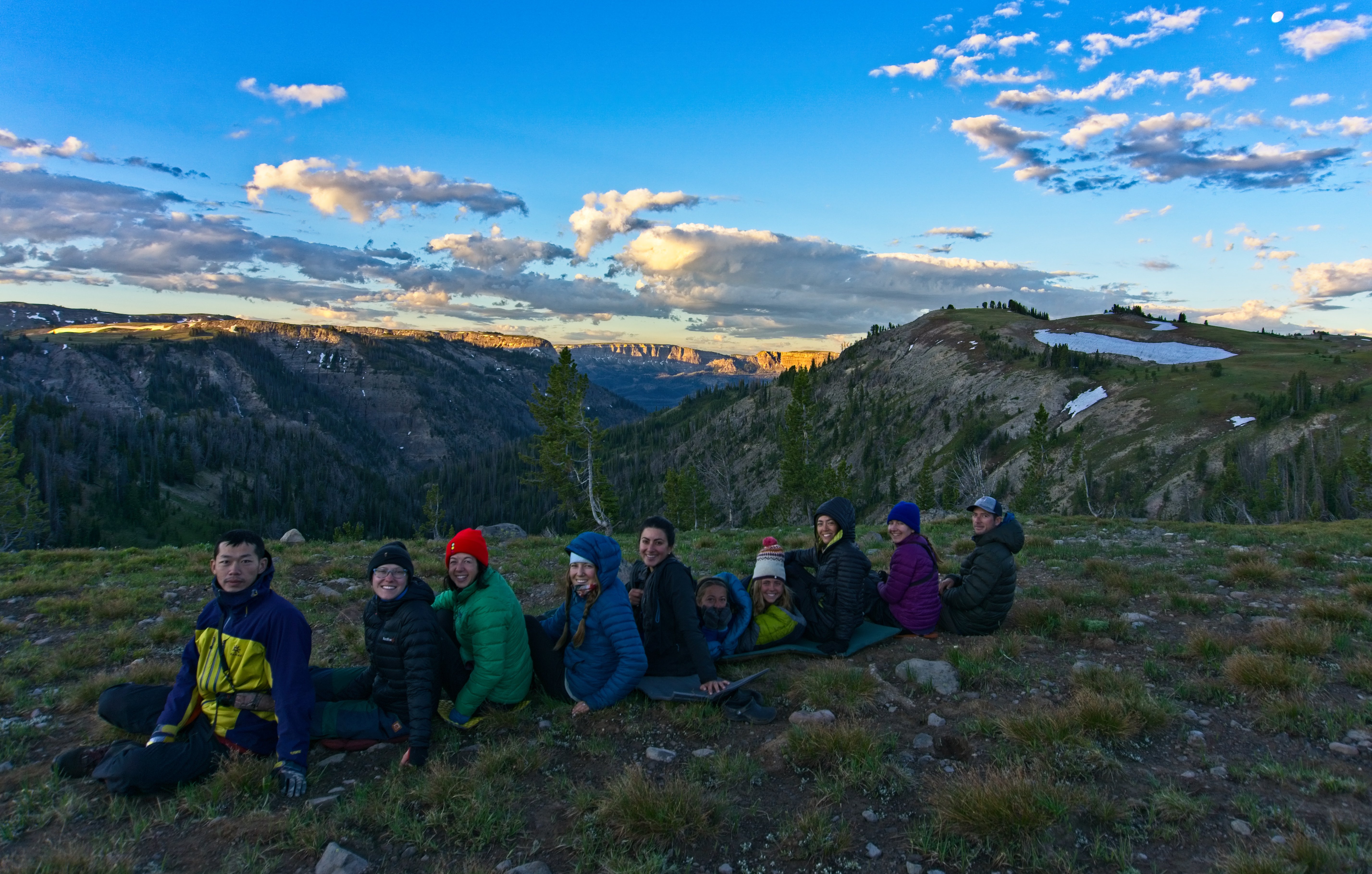 ten students sit in a line in the mountains at sunset