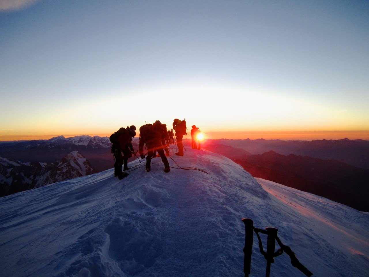 Mountaineers on a summit ridge with sunset in the background