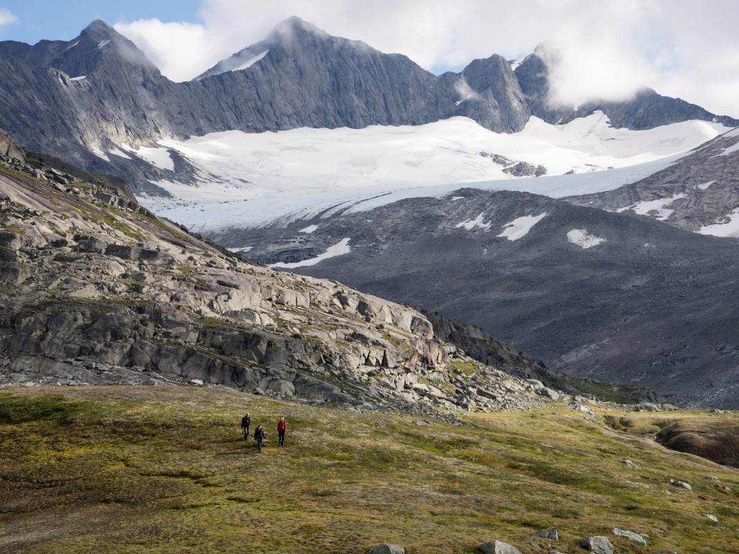 Hikers cross an alpine meadow in a stunning mountain landscape