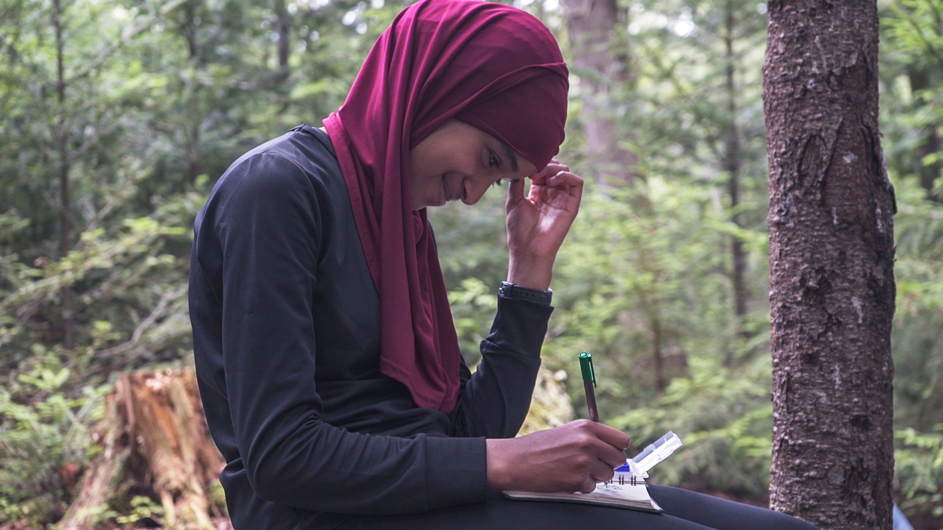 A student smiles while writing in the Adirondacks
