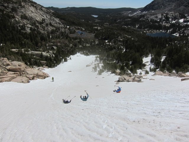 NOLS participants practice self-arrest with trekking poles on a snowy slope in the Wind River Range