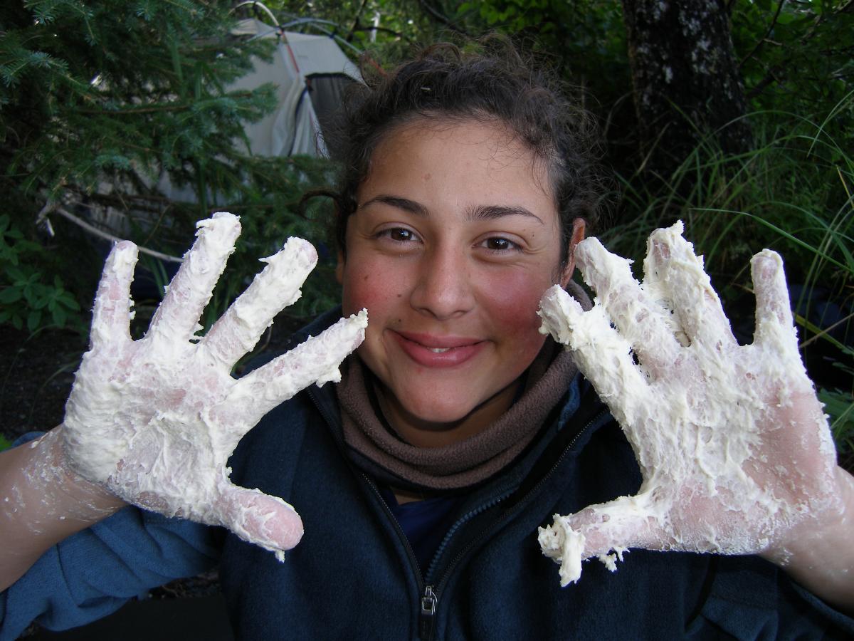 Happy student with bread dough on her hands