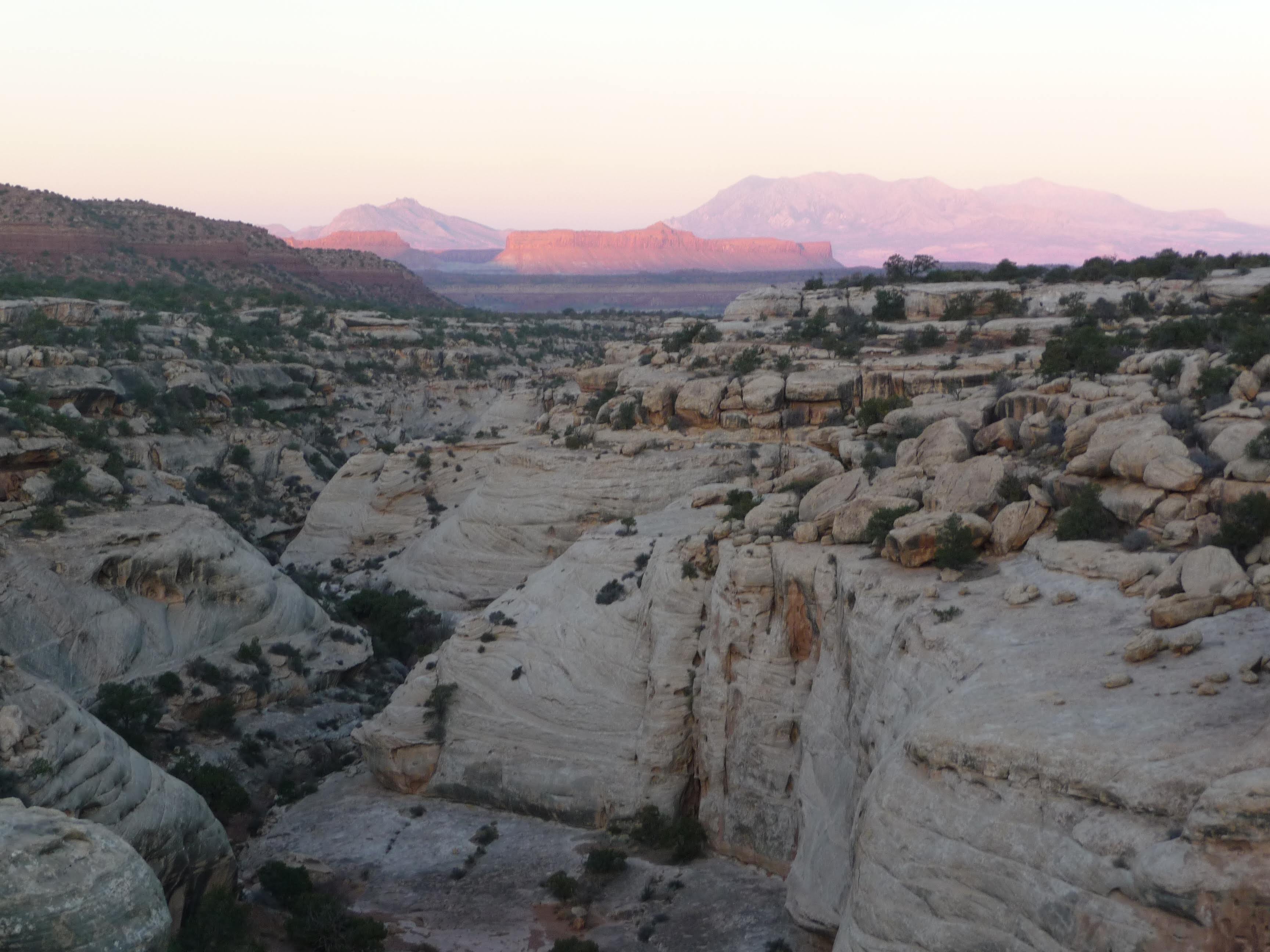 Canyonlands in Utah with sun rising over reddish rock formation in the distance