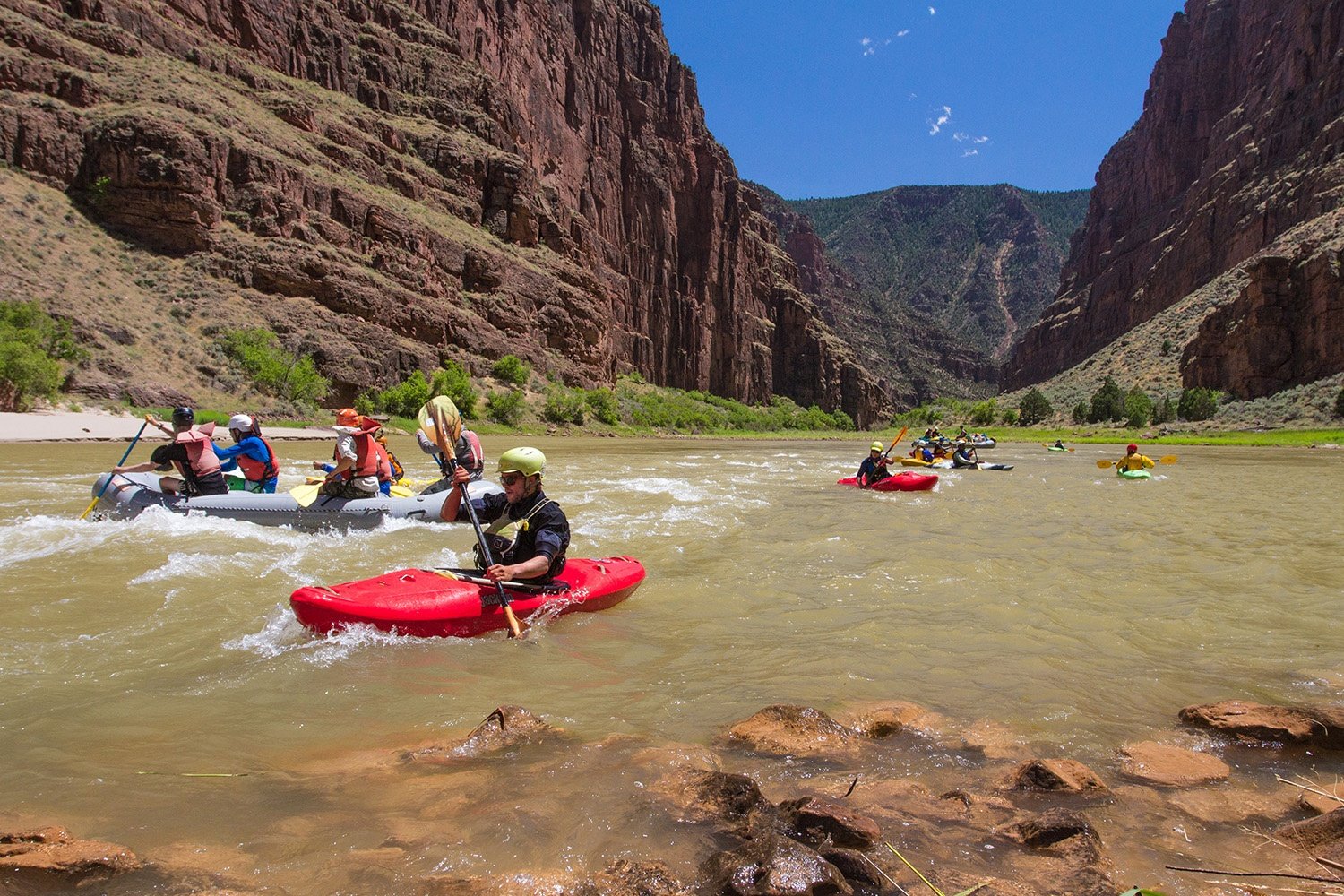 Students raft down a river in a desert canyon