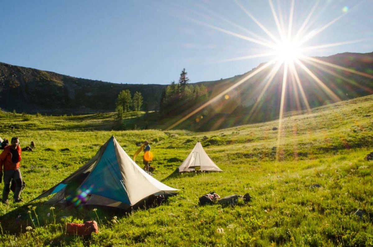 Setting up tents in a grassy valley