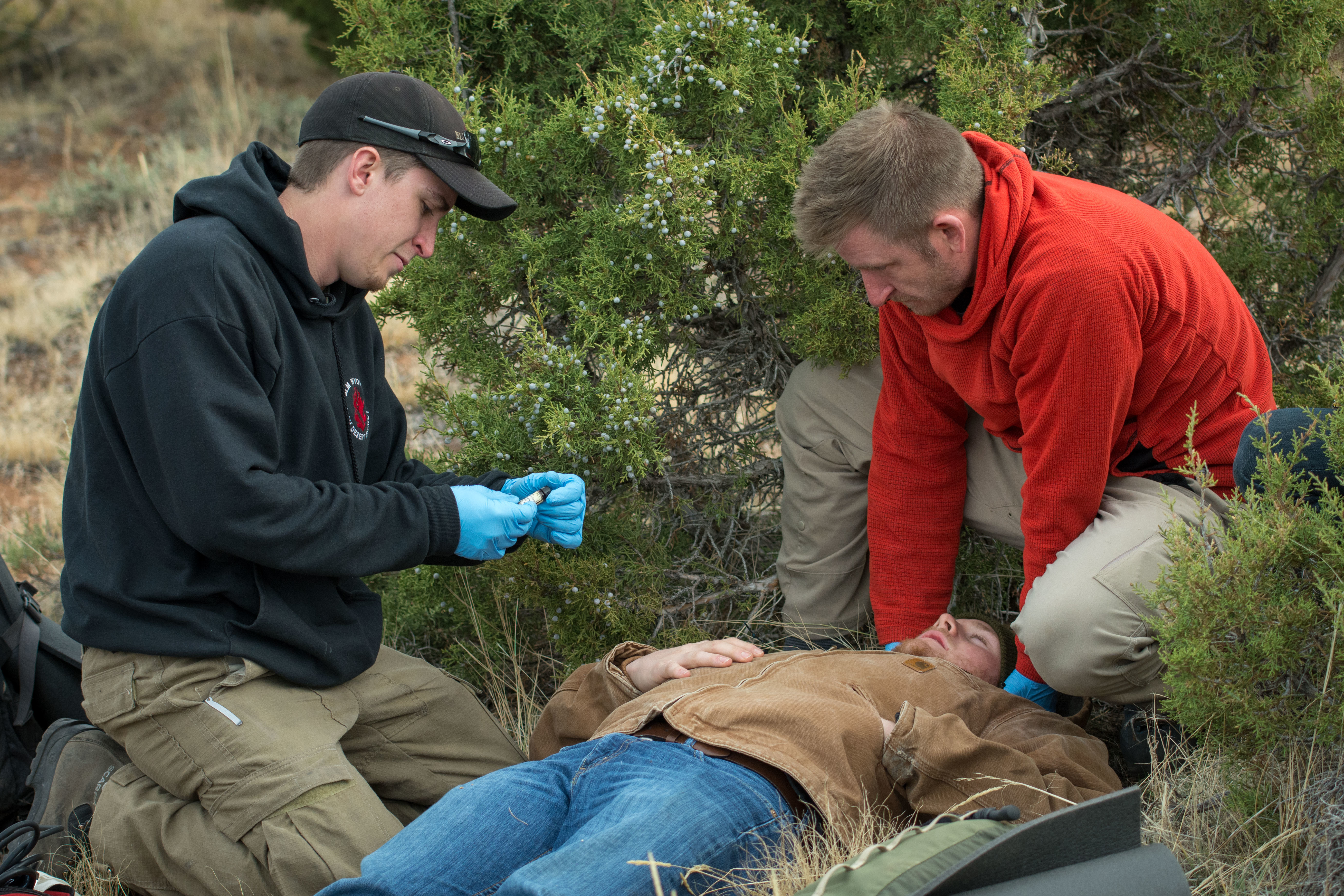 Two responders take the vitals of a patient in the backcountry during a scenario on a NOLS course