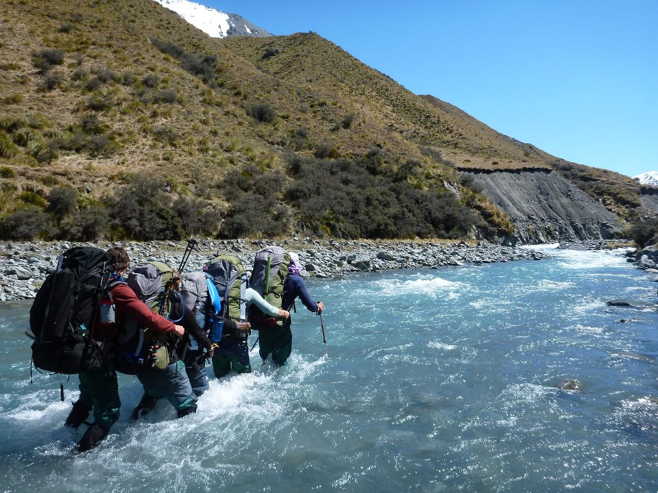 A group of backpackers crosses a river using the eddy line method